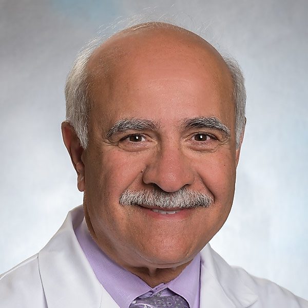 Portrait of an elderly male doctor with a mustache in a white coat.