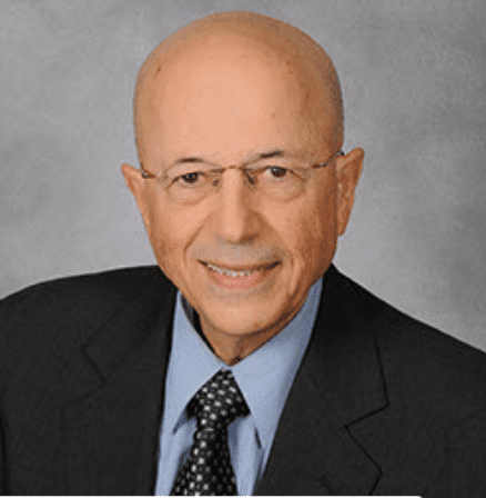 Professional headshot of a bald man in glasses and suit.