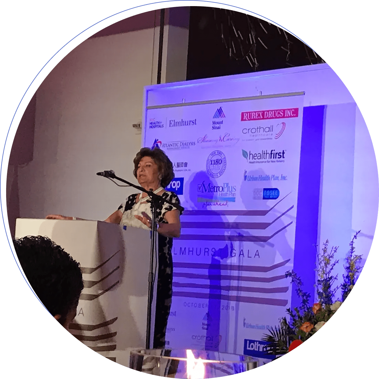 Speaker presenting at a professional conference with a microphone and podium.