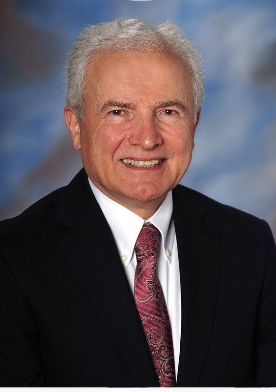 Portrait of a smiling elderly man in a suit and tie.