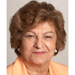 Portrait of a mature woman with short curly hair and a peach blouse.