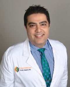 A smiling male doctor in a white coat and green tie.