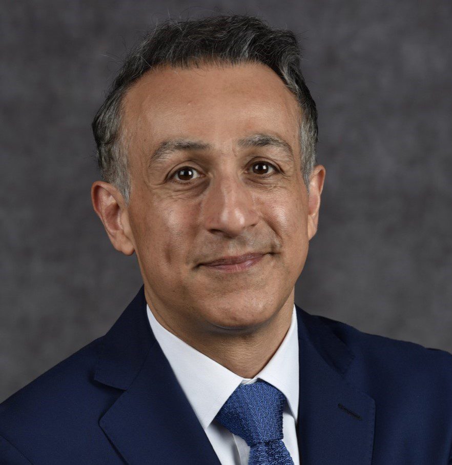 Professional man in a blue suit with a gray background.