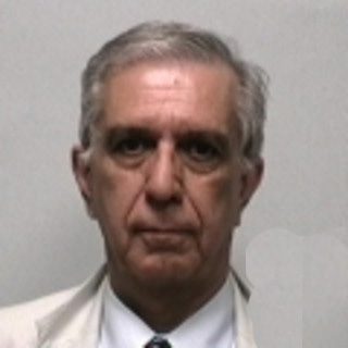 Portrait of an older man in a white shirt against a plain background.