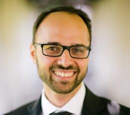 Smiling man wearing glasses and a suit jacket.