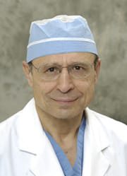 Portrait of a senior male doctor in medical attire and cap.