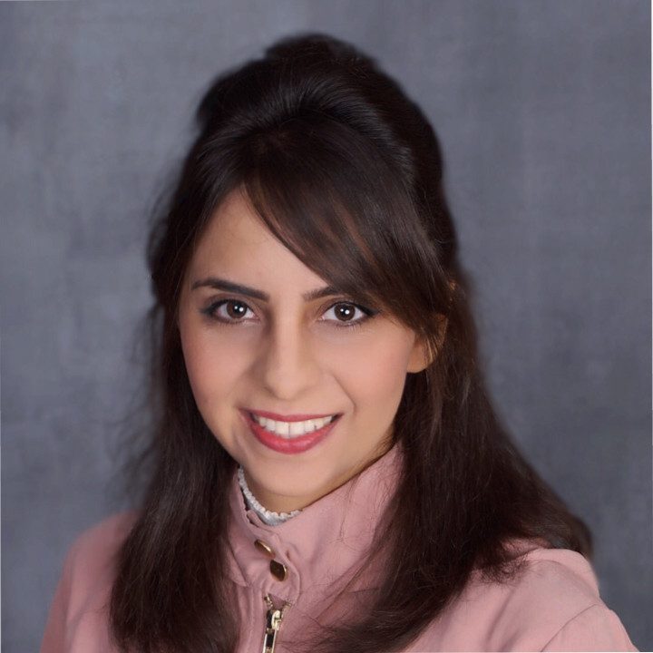 Professional woman with dark hair smiling against a gray backdrop.